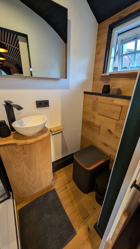 Modernes Bad mit Holz-Waschtisch, Aufsatzwaschbecken, Spiegel und Fenster.