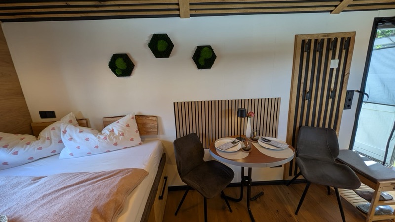 Gemütlicher Wohn- und Essbereich mit Doppelbett, Essecke und Moos-Wandbildern.